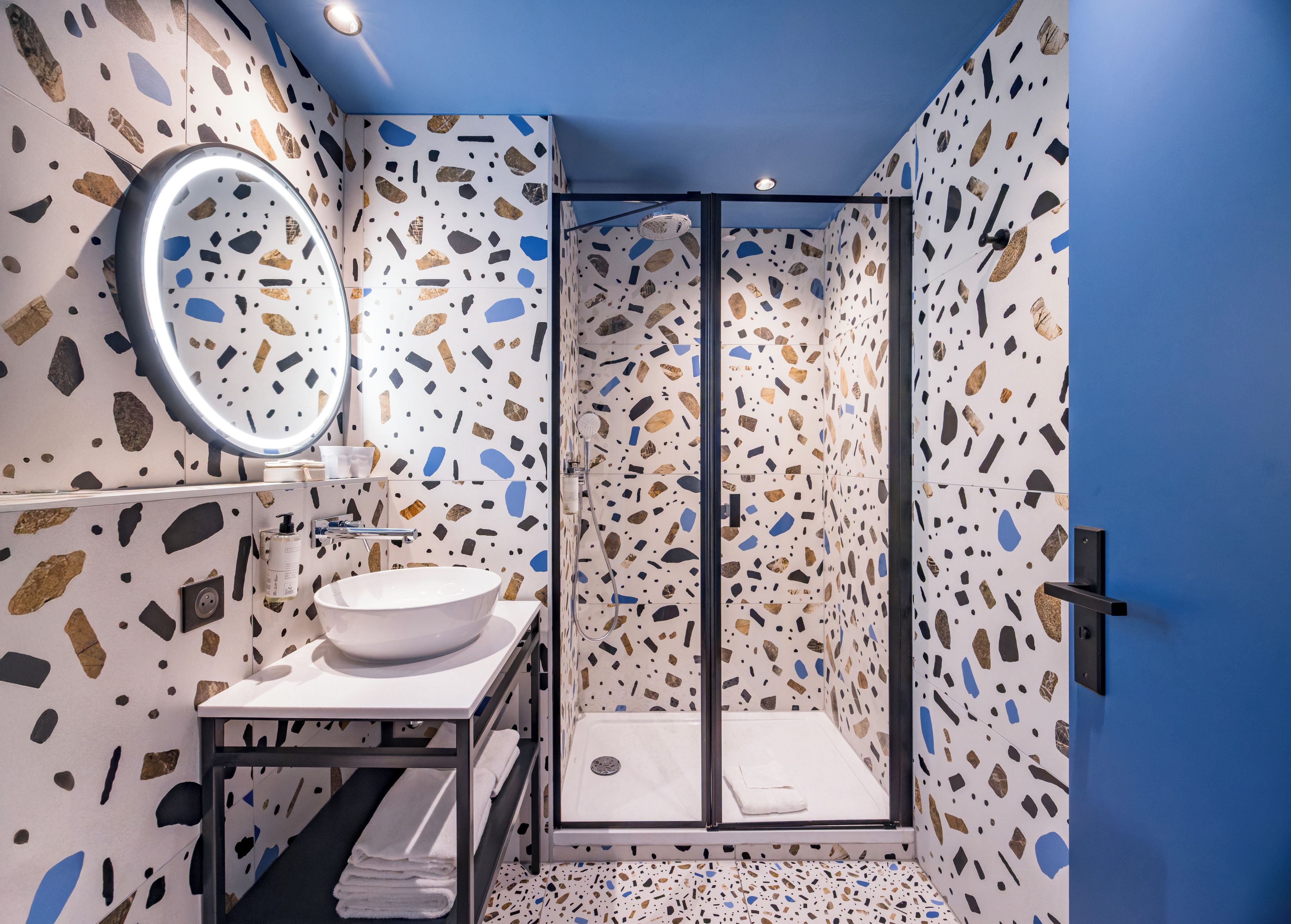 A bathroom with a white sink, a round mirror, and a shower with a glass door.