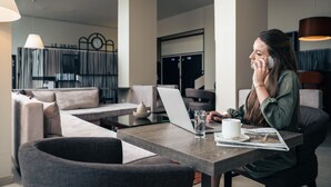 A modern interior with a sofa, a table with a laptop, a glass of water, and a cup. - Le Grand Hotel By Stay Collection (Strasbourg)