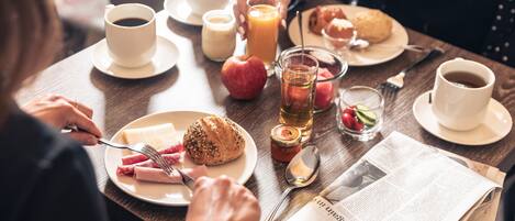Un desayuno con un plato de comida, un vaso de jugo, una taza de café y un periódico.
