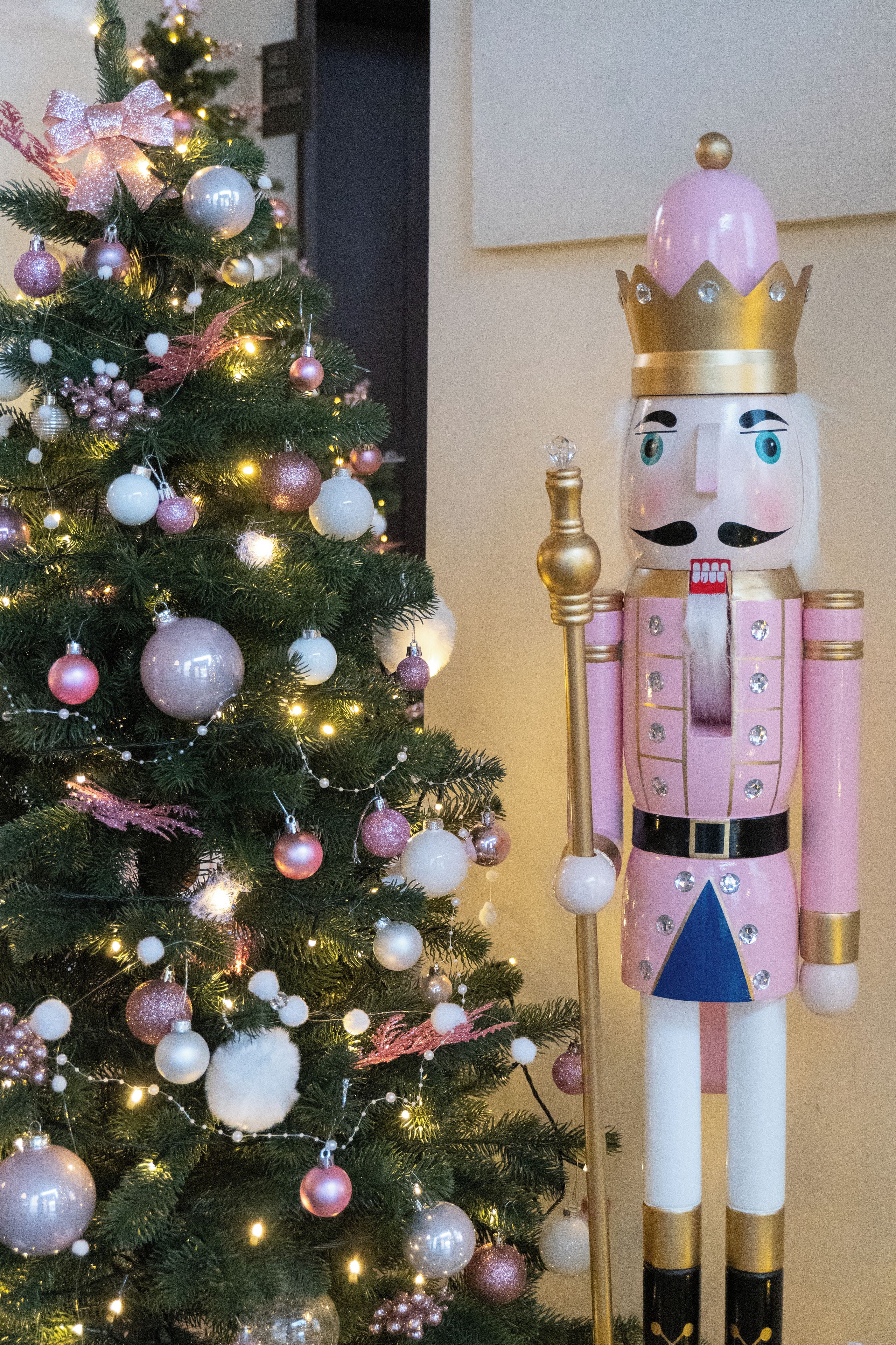 A nutcracker figure next to a Christmas tree.