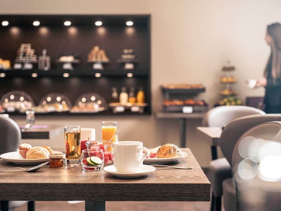 Taula de l'esmorzar amb pastissos, una tassa de cafè i un got de suc d'aranja.