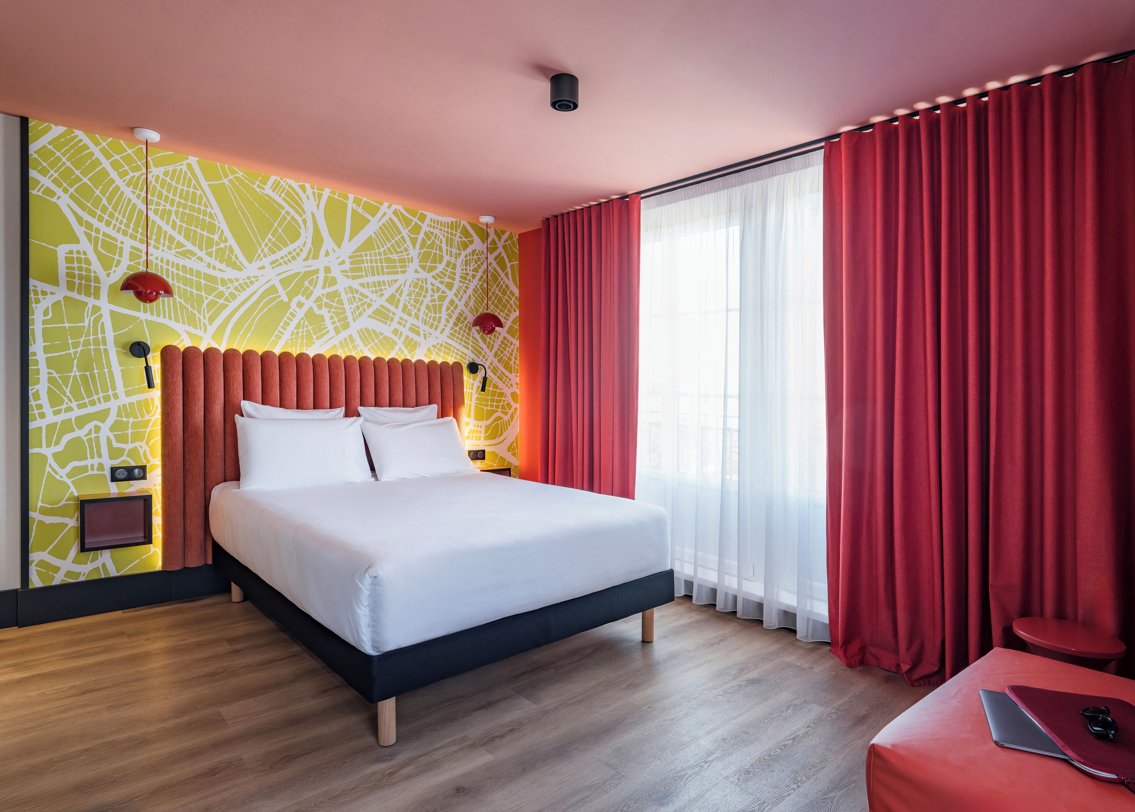 Une chambre d’hôtel moderne avec un grand lit, un bureau et un rideau rouge.