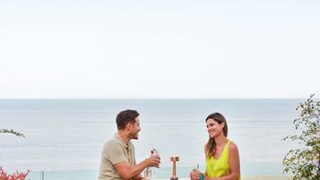 A couple seated at an outdoor table with a view of the ocean.
