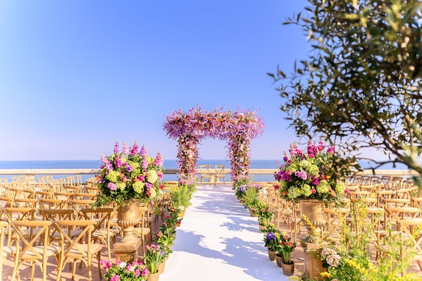 A beachside wedding aisle with wooden chairs and floral decorations. - Fairmont Monte Carlo (Monaco)