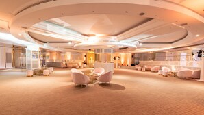 Un hall espacioso con una zona de estar central, un mostrador de recepción y un diseño de techo moderno.
