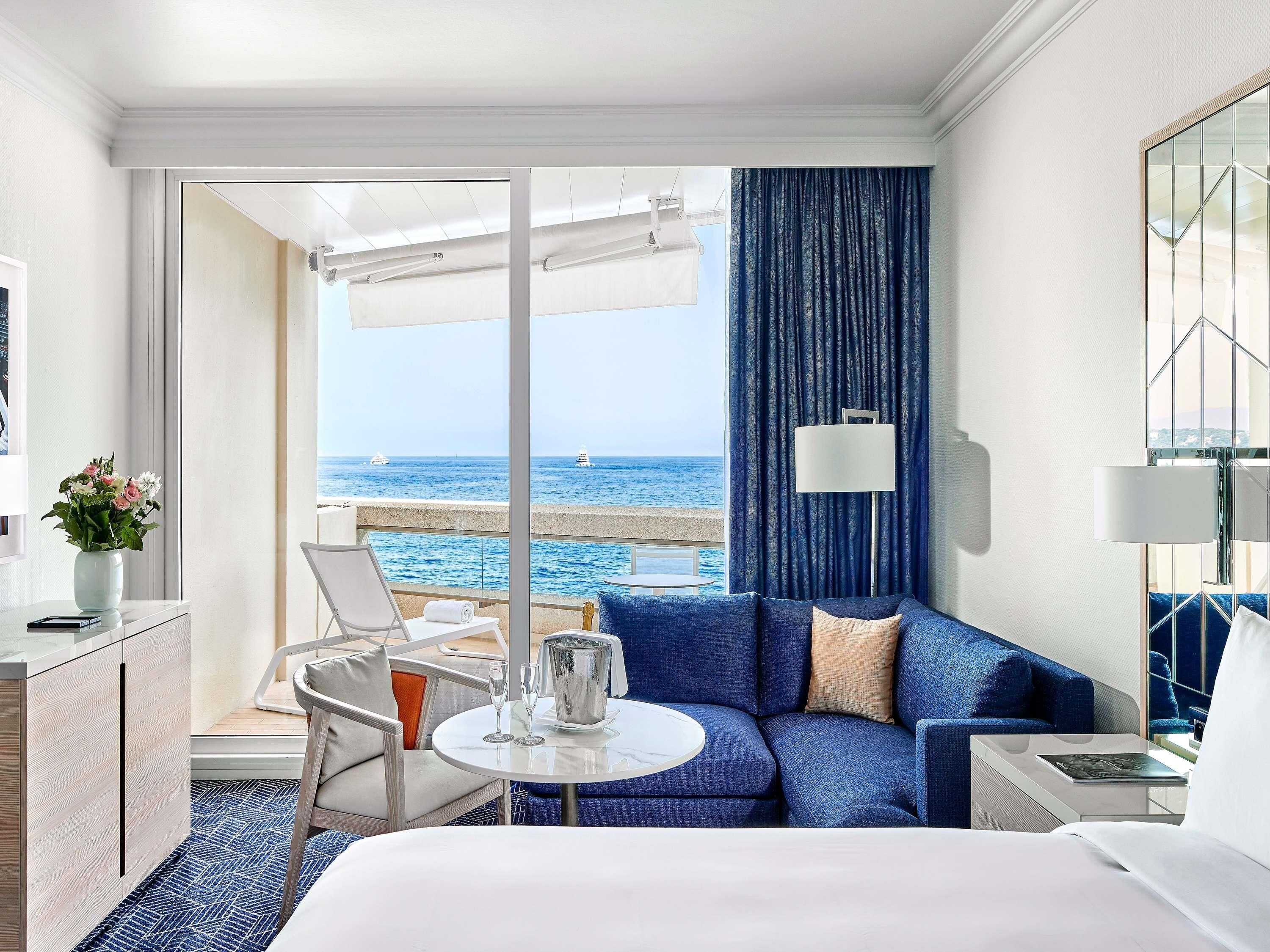 A hotel room with a balcony, a sofa, a table, and a bed.