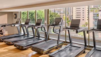 Un gimnasio con cintas de correr, cada una equipada con un ordenador portátil.