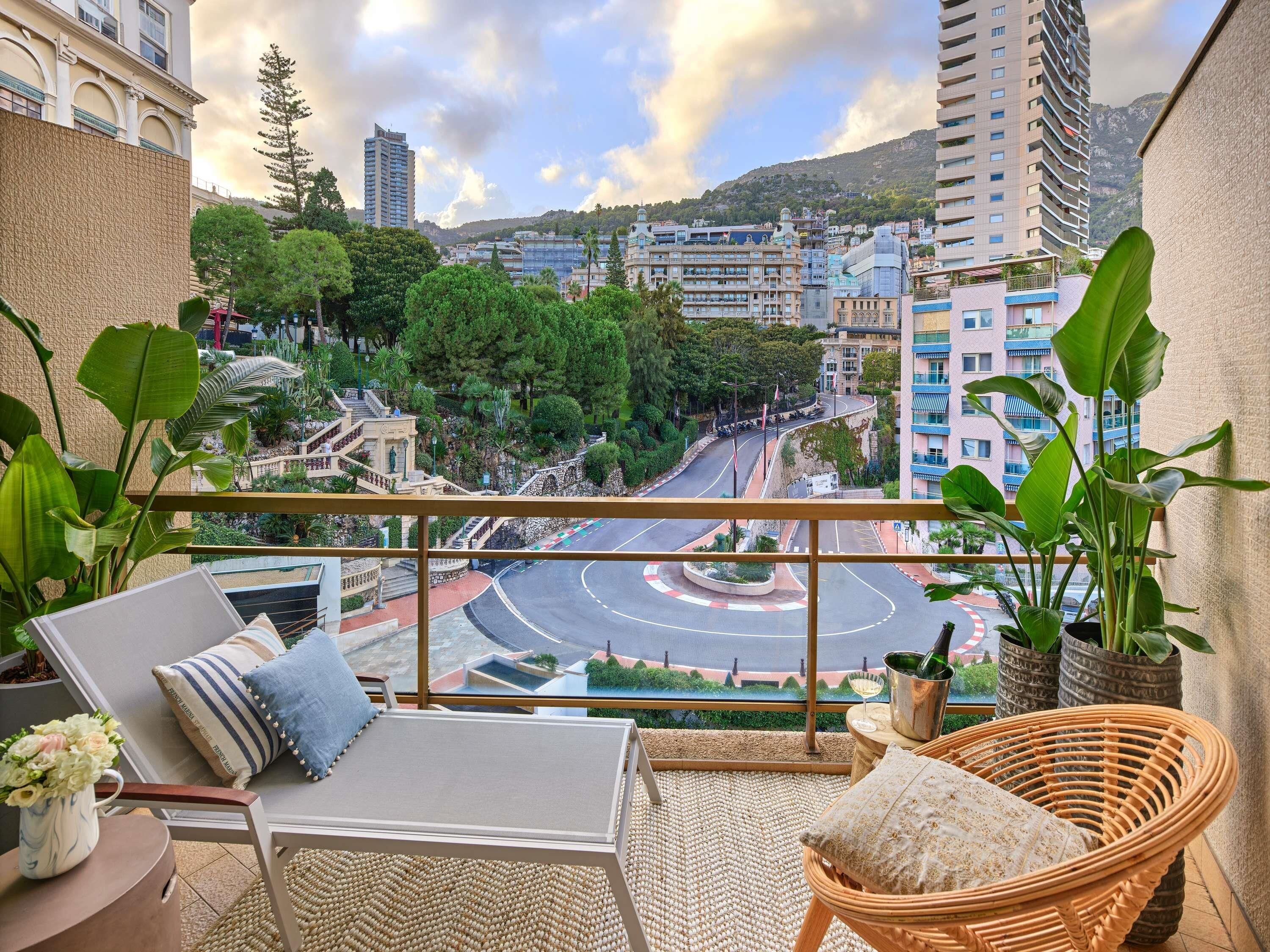 Un balcón con vista a un paisaje urbano, que incluye edificios y una glorieta.