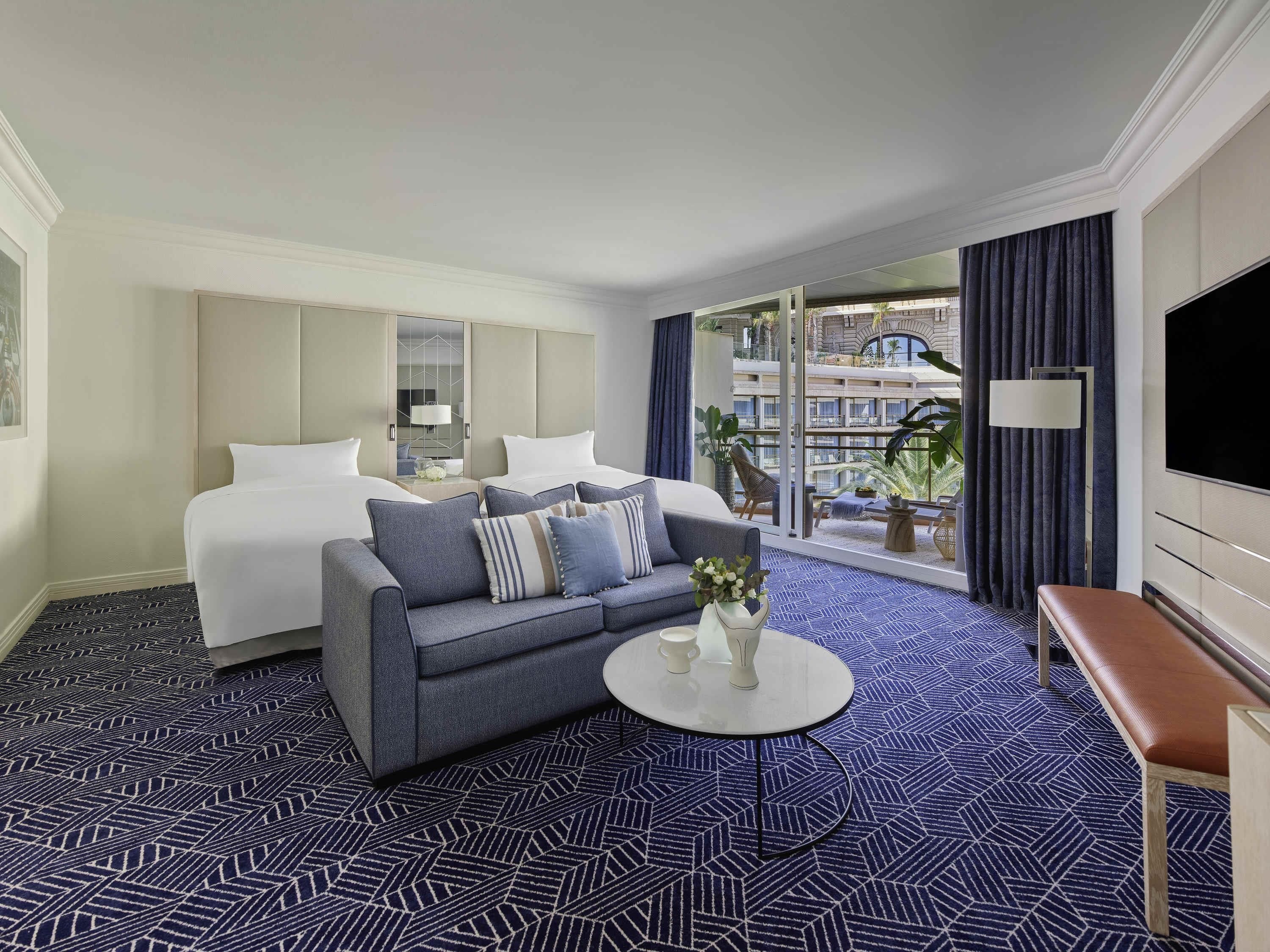 Una habitación de hotel con cama, sofá, mesa de centro y televisor.