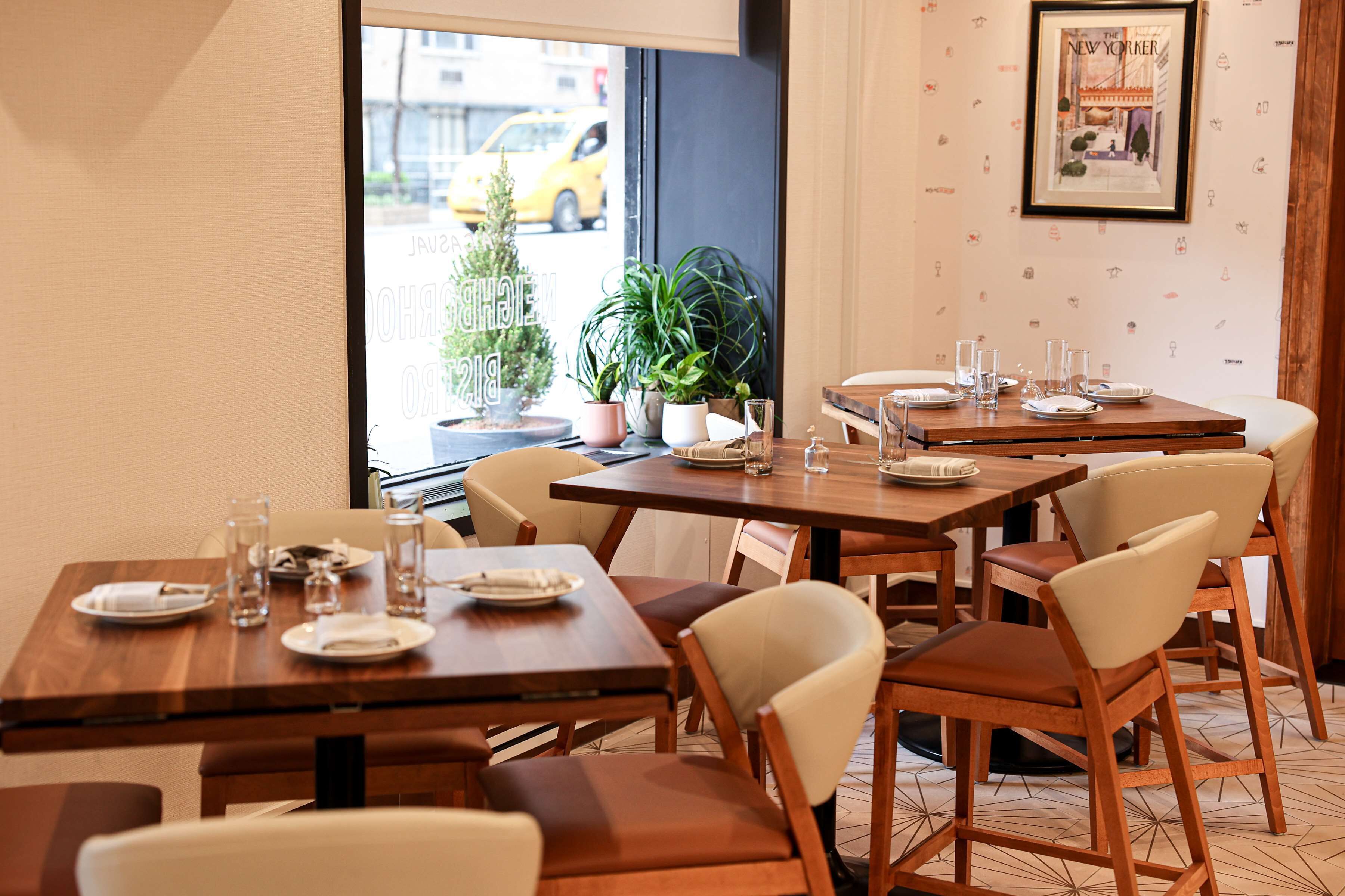 Un restaurante con mesas y sillas de madera, plantas en macetas y un cuadro en la pared.