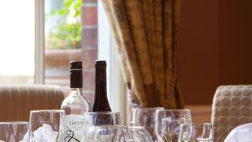 A table set with wine glasses and bottles, a window with a view of greenery, and a patterned wall.