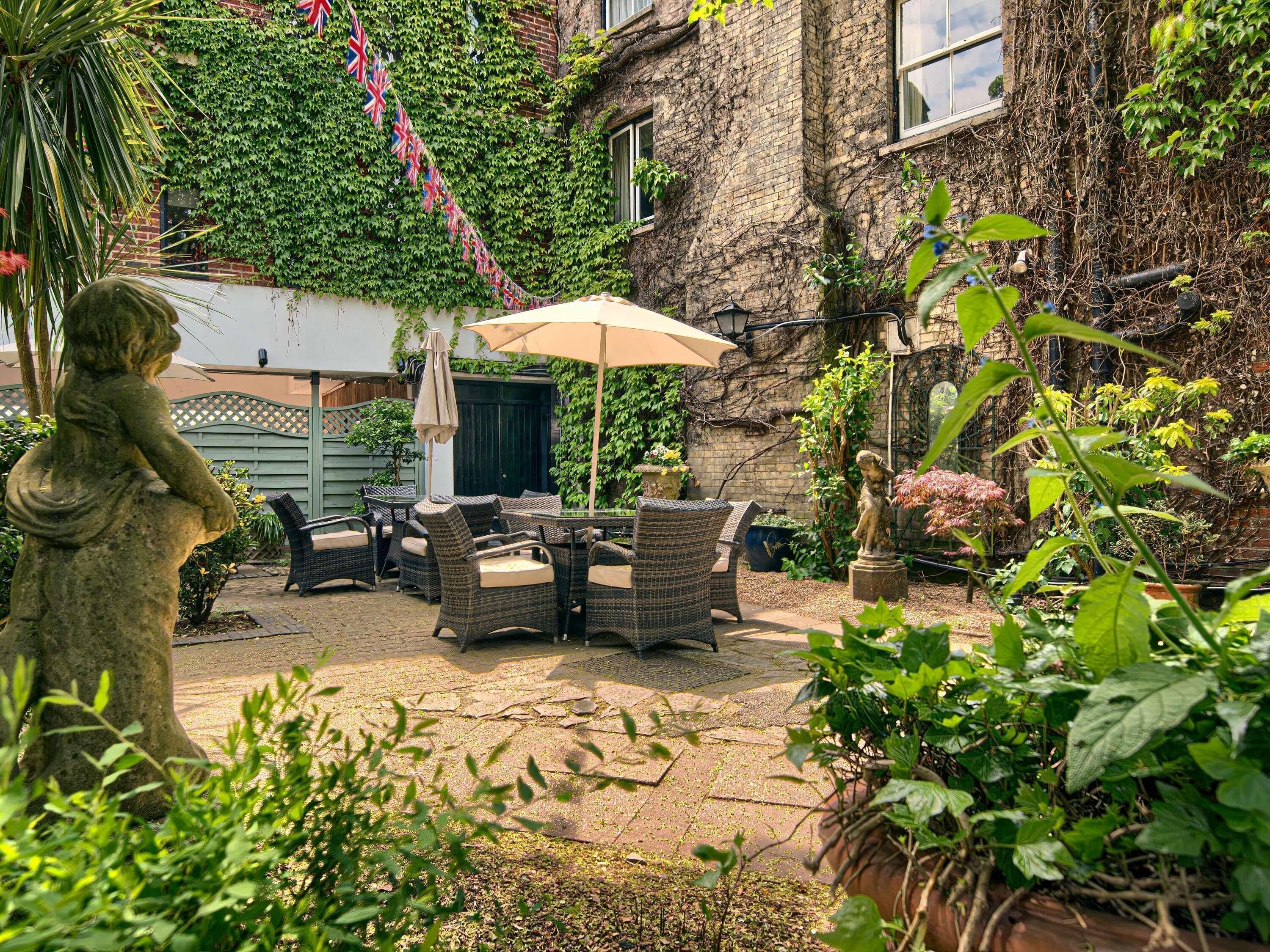 A patio area with wicker furniture, a statue, and potted plants.