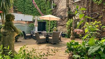 A patio area with wicker furniture, a statue, and potted plants.