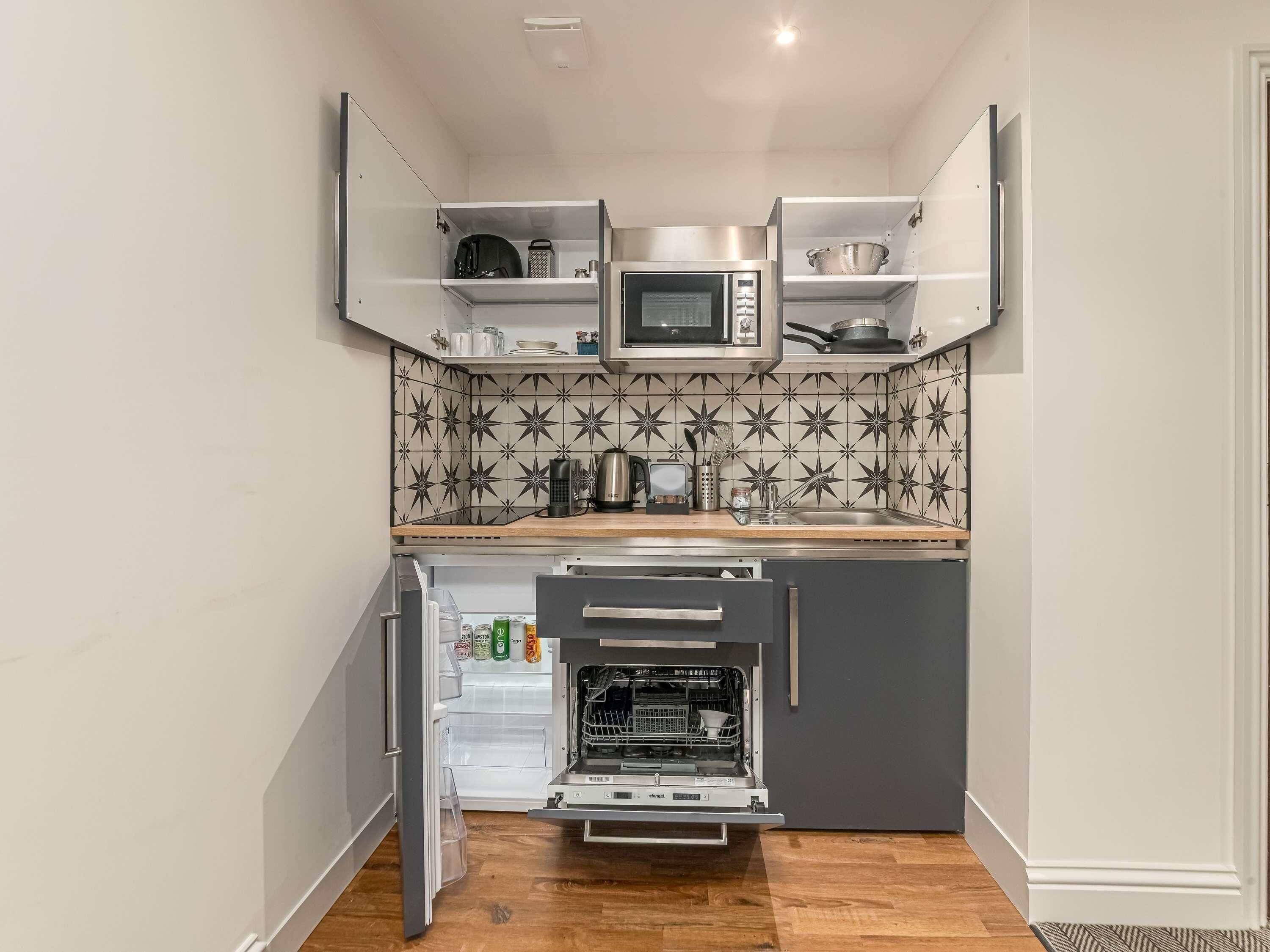 A compact kitchen with a microwave, kettle, and a built-in oven.