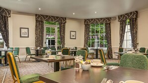A hotel dining area with multiple tables, chairs, and a view of greenery outside. - Mercure White Hart Hotel Salisbury and Apartments (Salisbury)