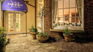 A Mercure hotel entrance with a stone pathway, potted plants, and a brick building facade. - Mercure White Hart Hotel Salisbury and Apartments (Salisbury)