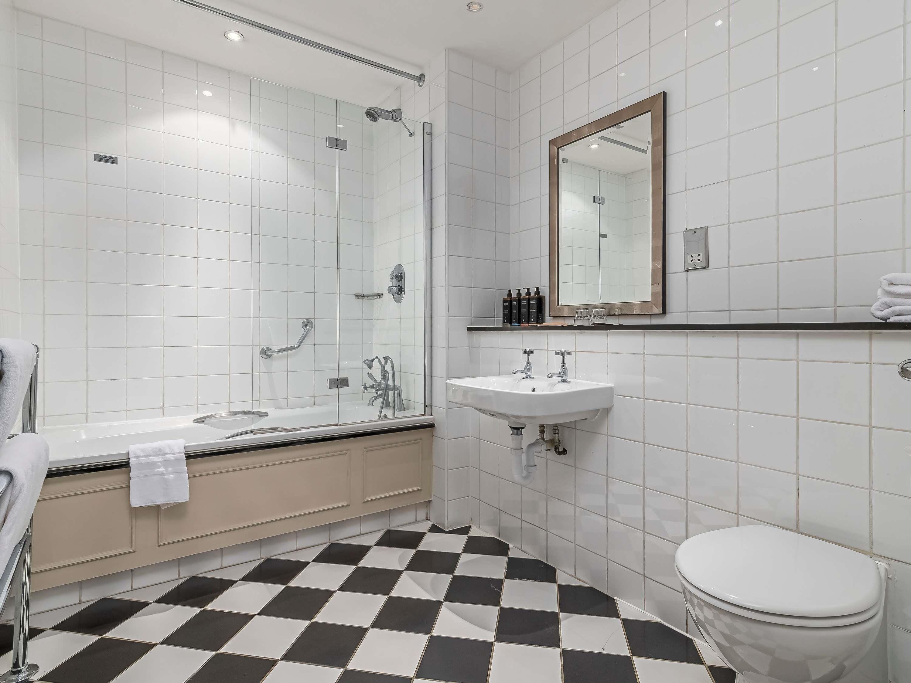 A modern bathroom with a glass-enclosed shower, a white sink, and a toilet.