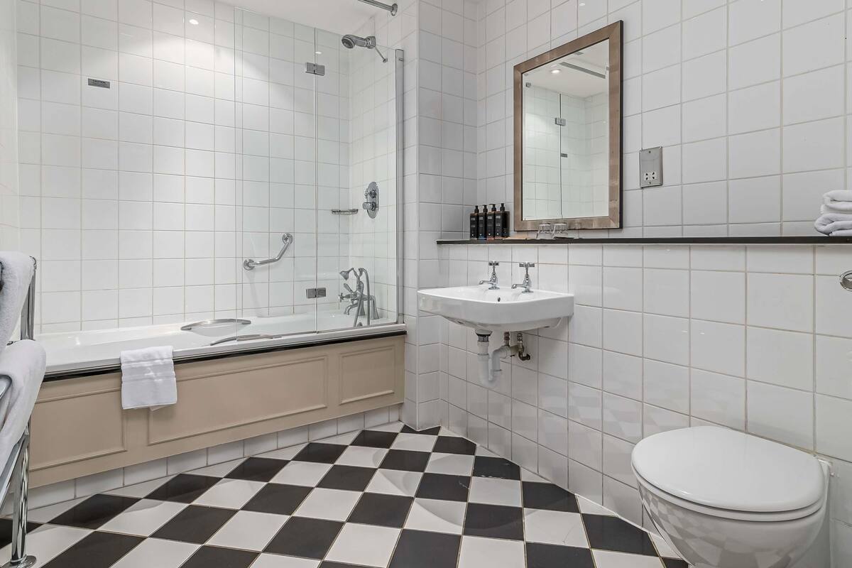 A modern bathroom with a glass-enclosed shower, a white sink, and a toilet.