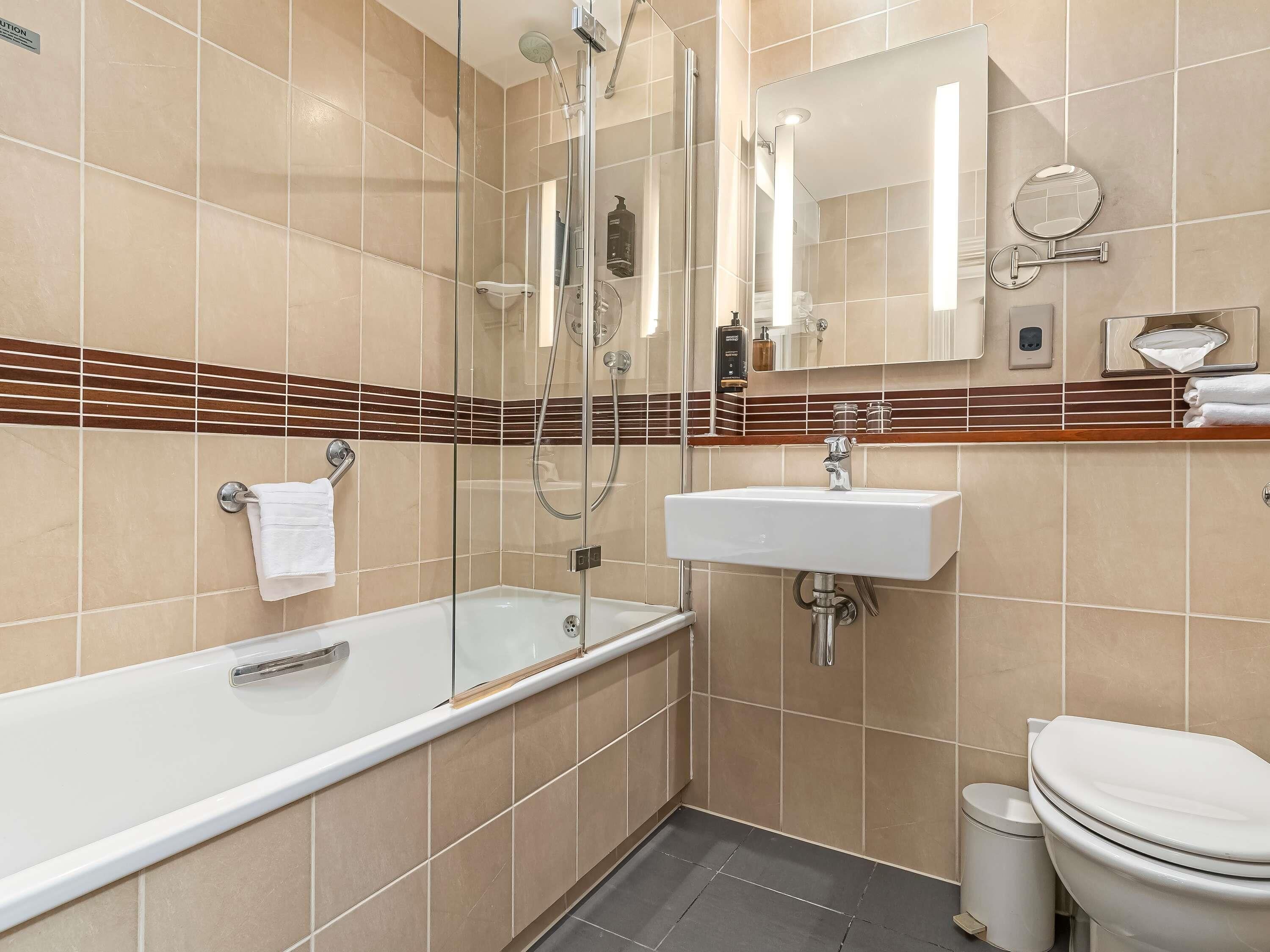 Un baño moderno con ducha de vidrio, lavamanos blanco y retrete.