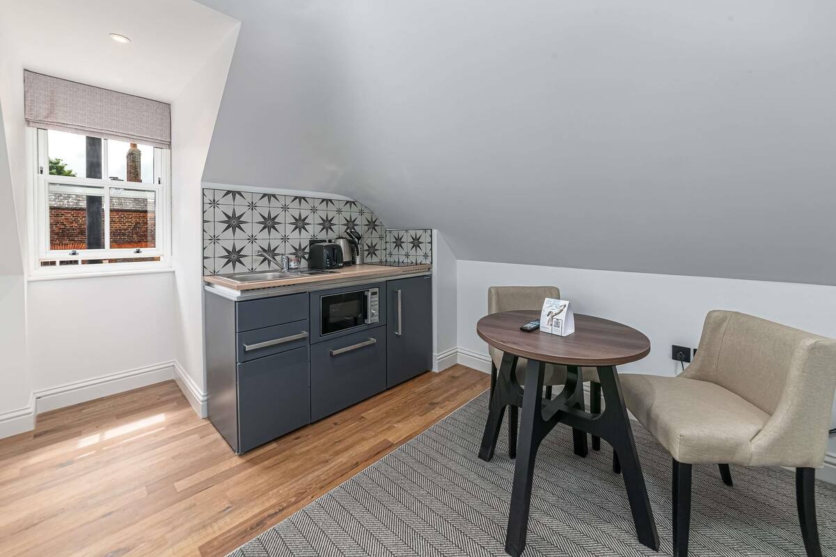 A compact kitchen with a modern design, including a built-in microwave and a coffee maker.