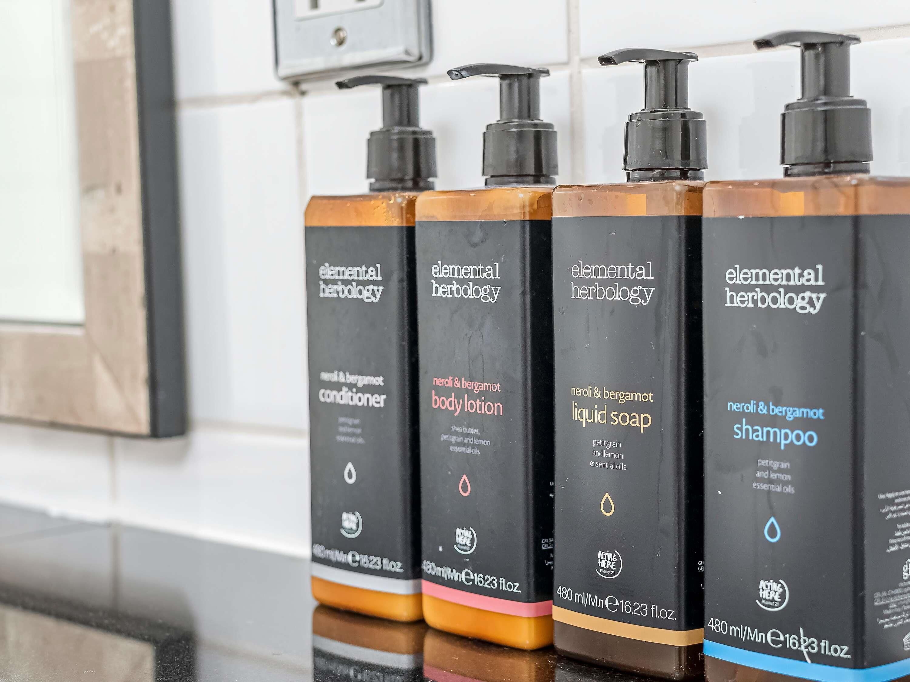 A row of four Elemental Herbology personal care products on a reflective surface.