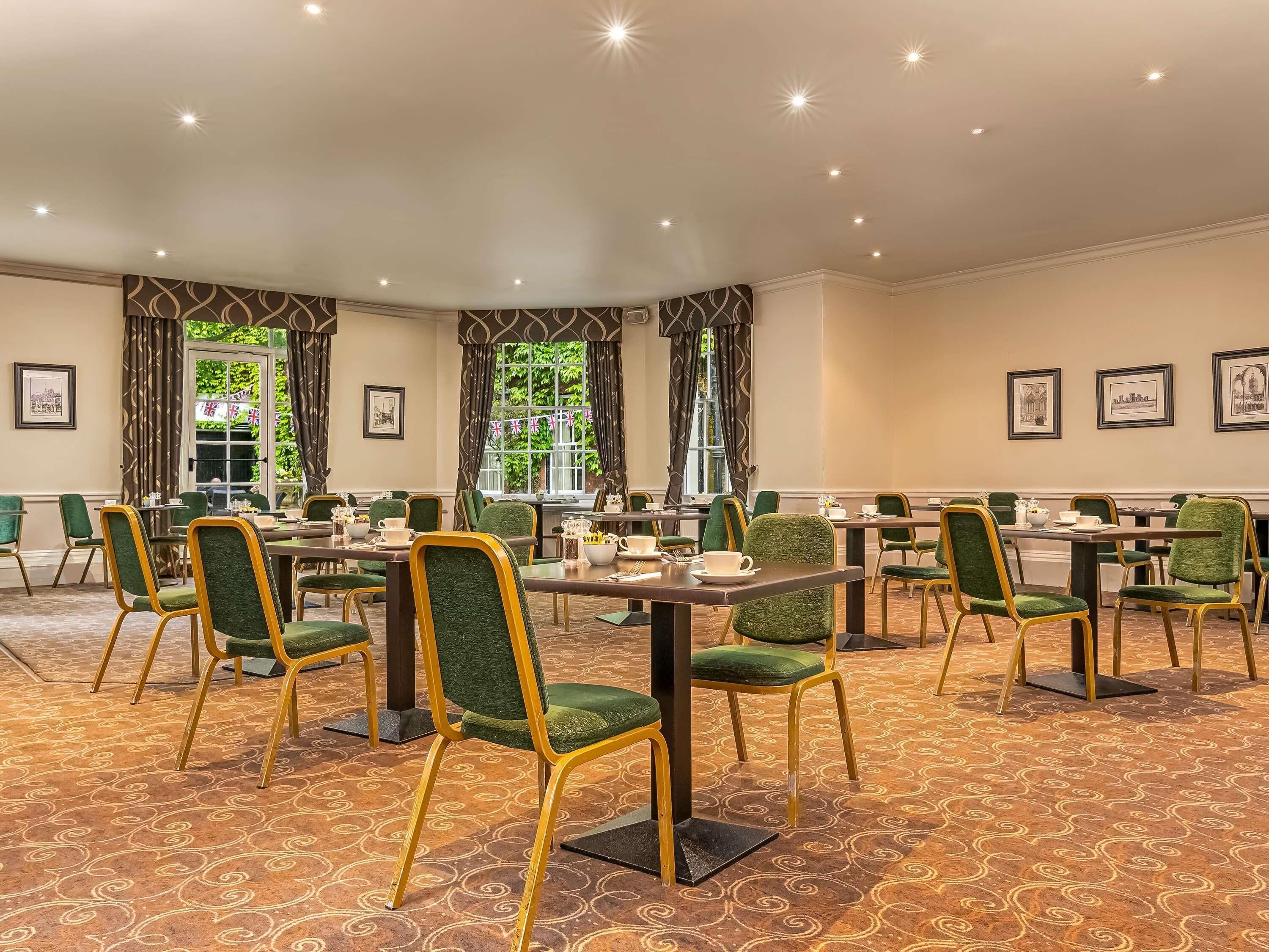 A conference room with green upholstered chairs, a patterned carpet, and framed pictures on the walls.