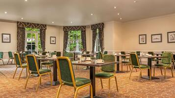A conference room with green upholstered chairs, a patterned carpet, and framed pictures on the walls.