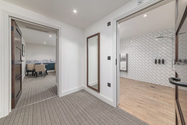 A modern hotel room with a large mirror, a wooden floor, and a tiled wall. - Mercure White Hart Hotel Salisbury and Apartments (Salisbury)
