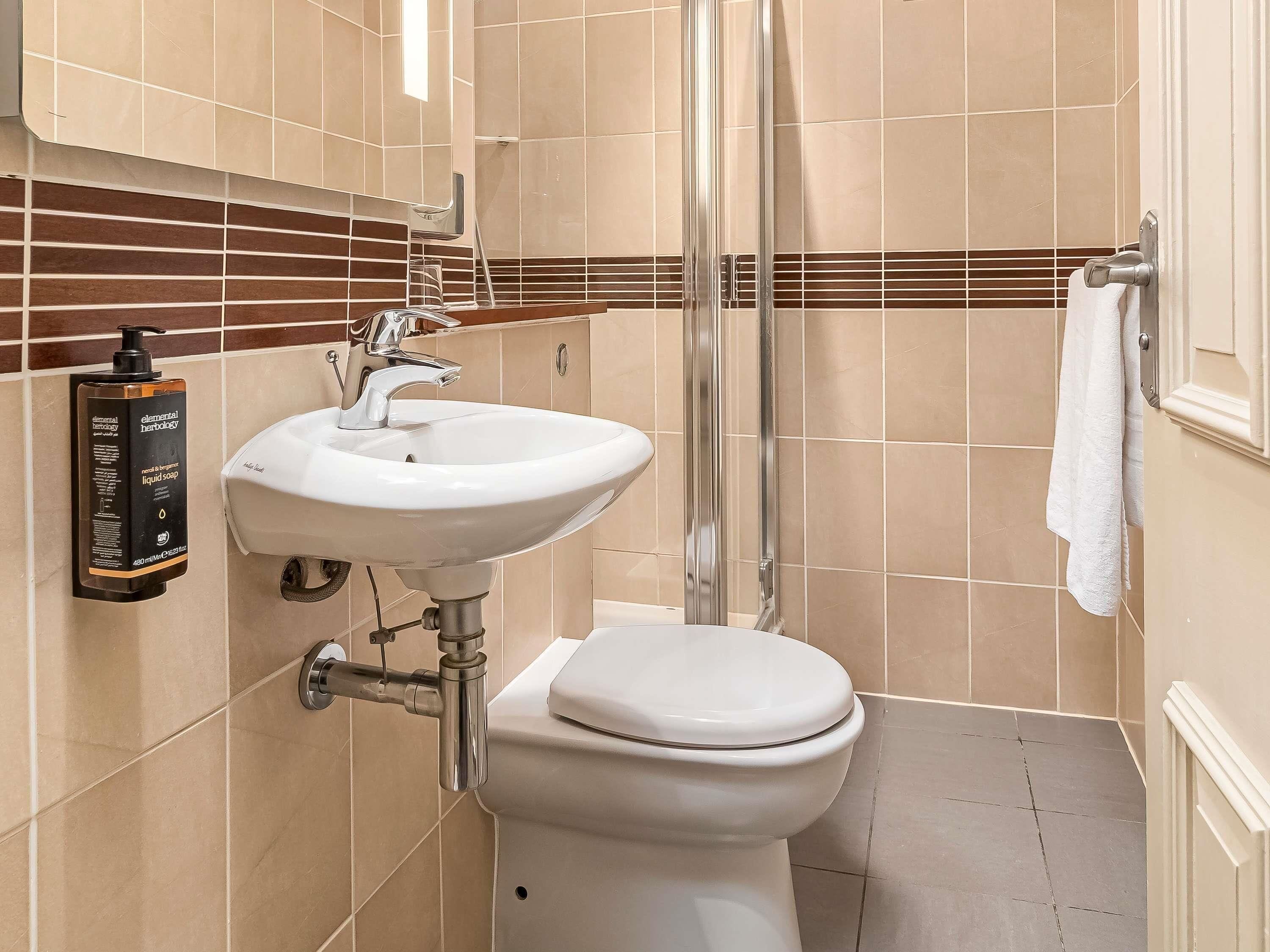 A bathroom with a white sink, a toilet, and a shower.