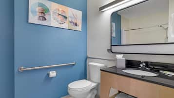 A bathroom with a toilet, sink, and a handrail.