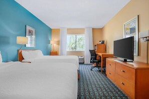 A hotel room with two beds, a desk, a television, and a window with a view of palm trees. - Sleep Inn & Suites (Pensacola)