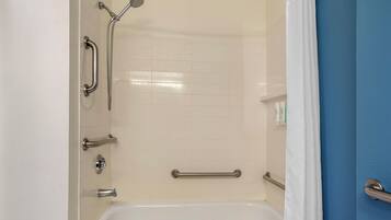 Baño con ducha, barras de apoyo y bañera.