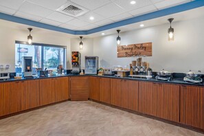 A breakfast area with a wooden counter, coffee machines, a refrigerator, and a sign that reads 'Morning Medley Breakfast'. - Sleep Inn & Suites Pensacola - University Area (Pensacola)