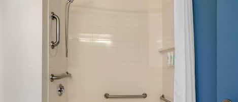 A bathroom with a shower, grab bars, and a bathtub.
