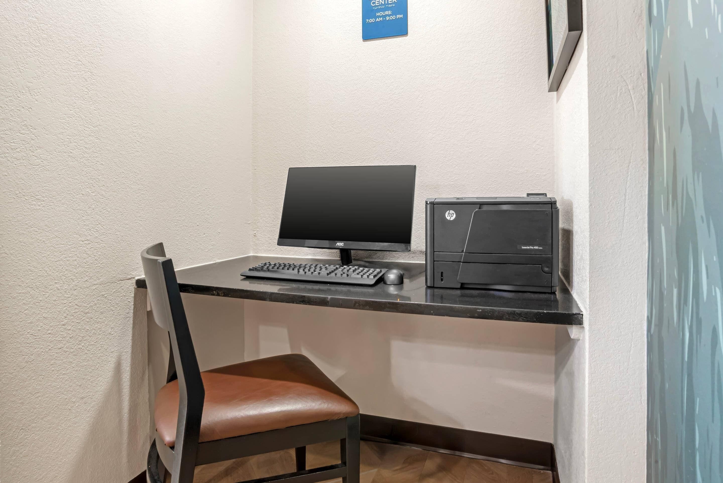 A small office space with a desk, a chair, a computer, and a printer.