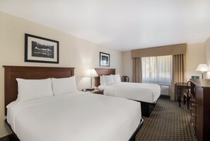 A hotel room with two beds, a desk, a chair, a lamp, and a framed picture on the wall. - Quality Inn & Suites Steamboat Springs (Steamboat Springs)