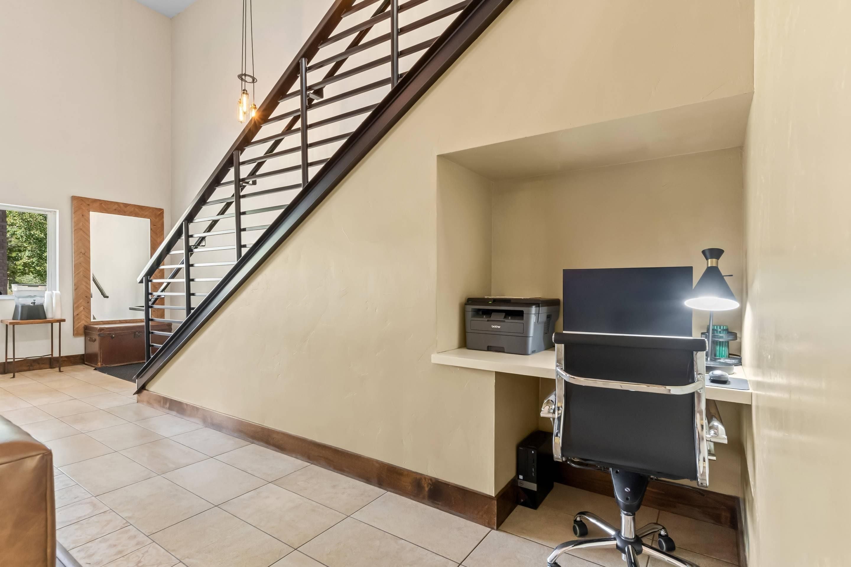 Una oficina en casa con escritorio, silla, impresora y una escalera.