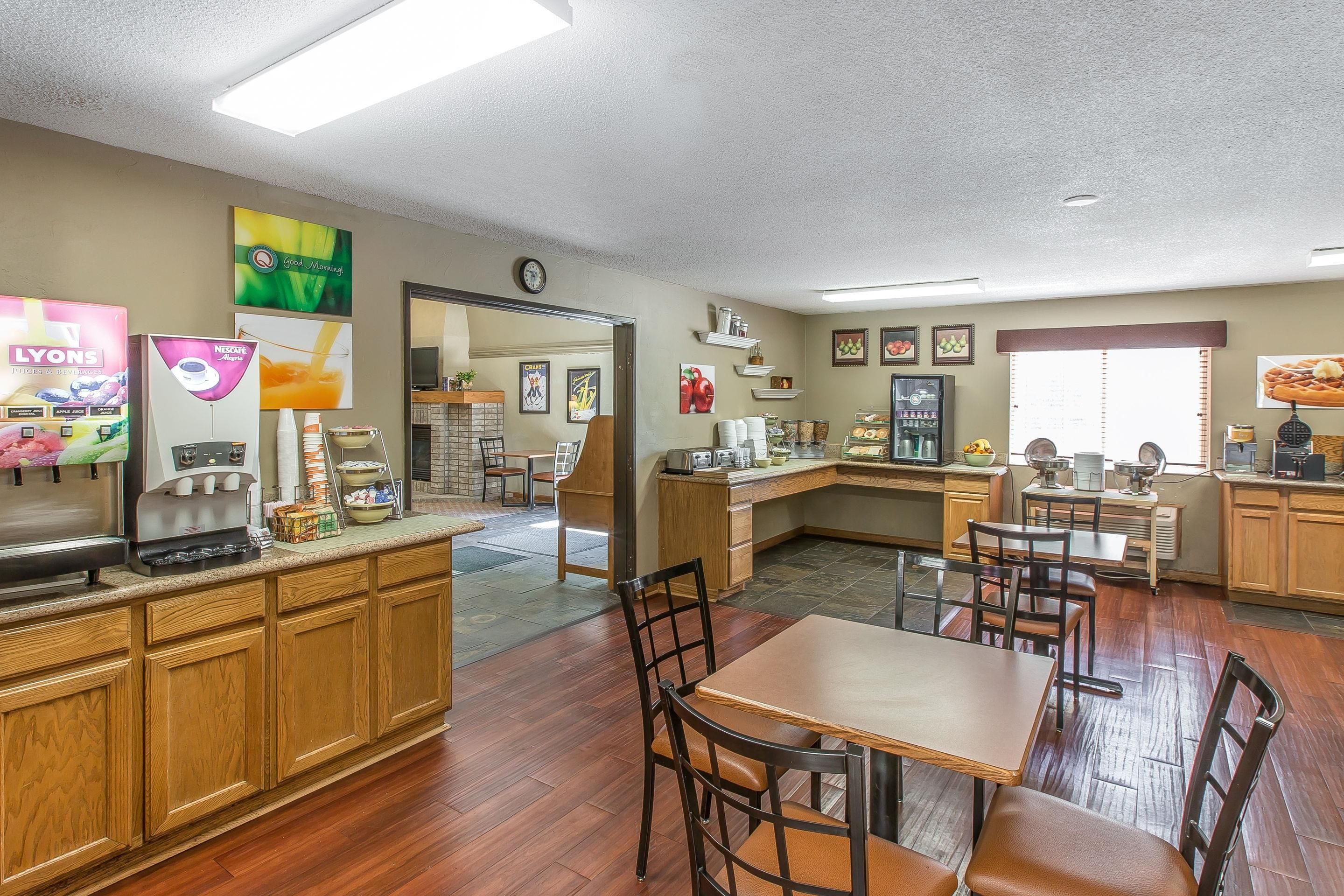 A spacious kitchen area with wooden cabinets, a coffee station, and a dining area with tables and chairs.