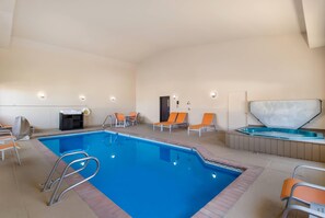 An indoor swimming pool with a clear blue water, surrounded by lounge chairs and a hot tub. - Quality Inn & Suites Steamboat Springs (Steamboat Springs)