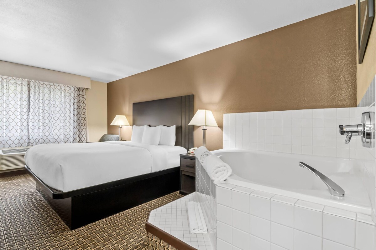A hotel room with two beds, a large bathtub, and a separate shower area.