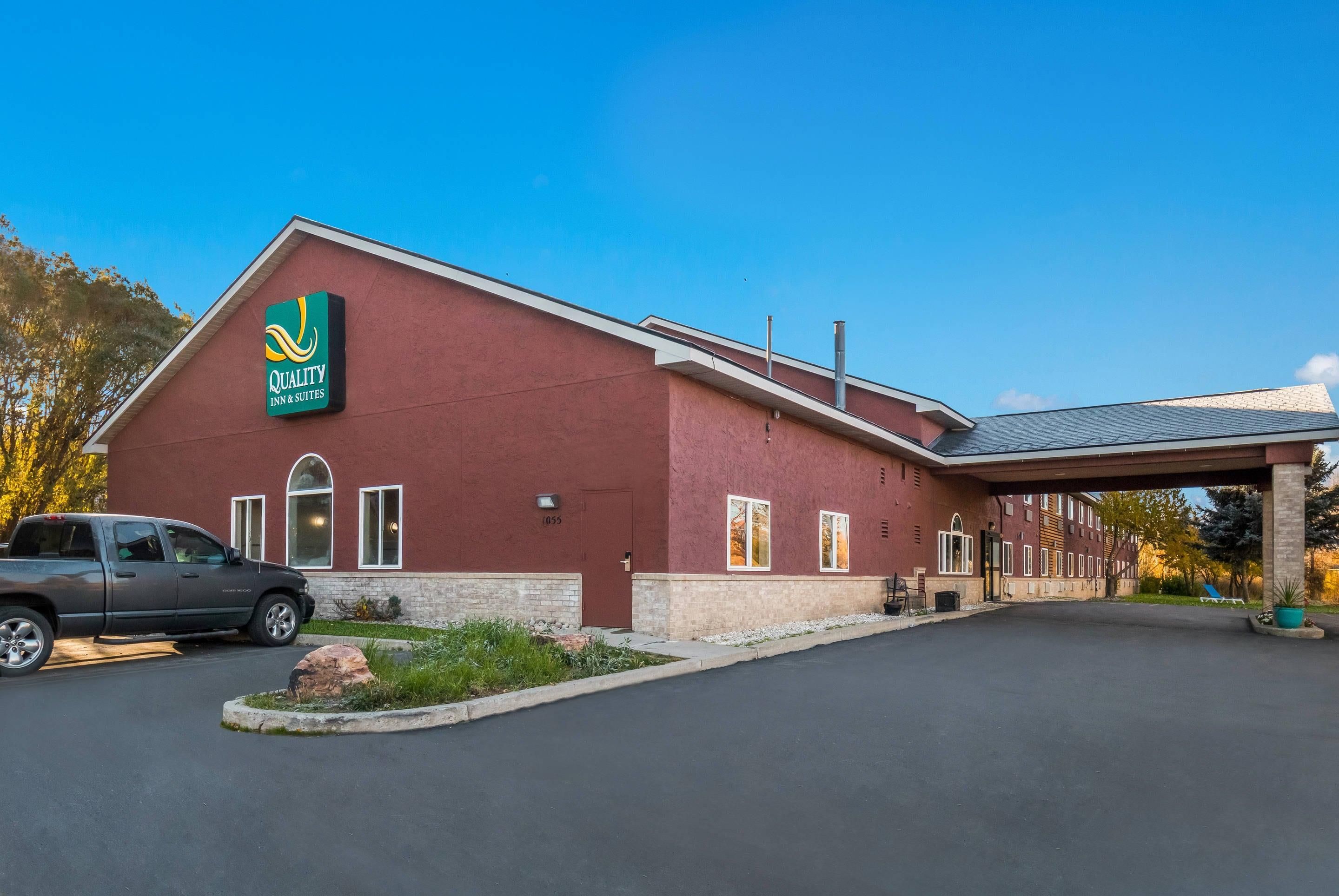 A red building with a green and yellow sign for Quality Inn & Suites.