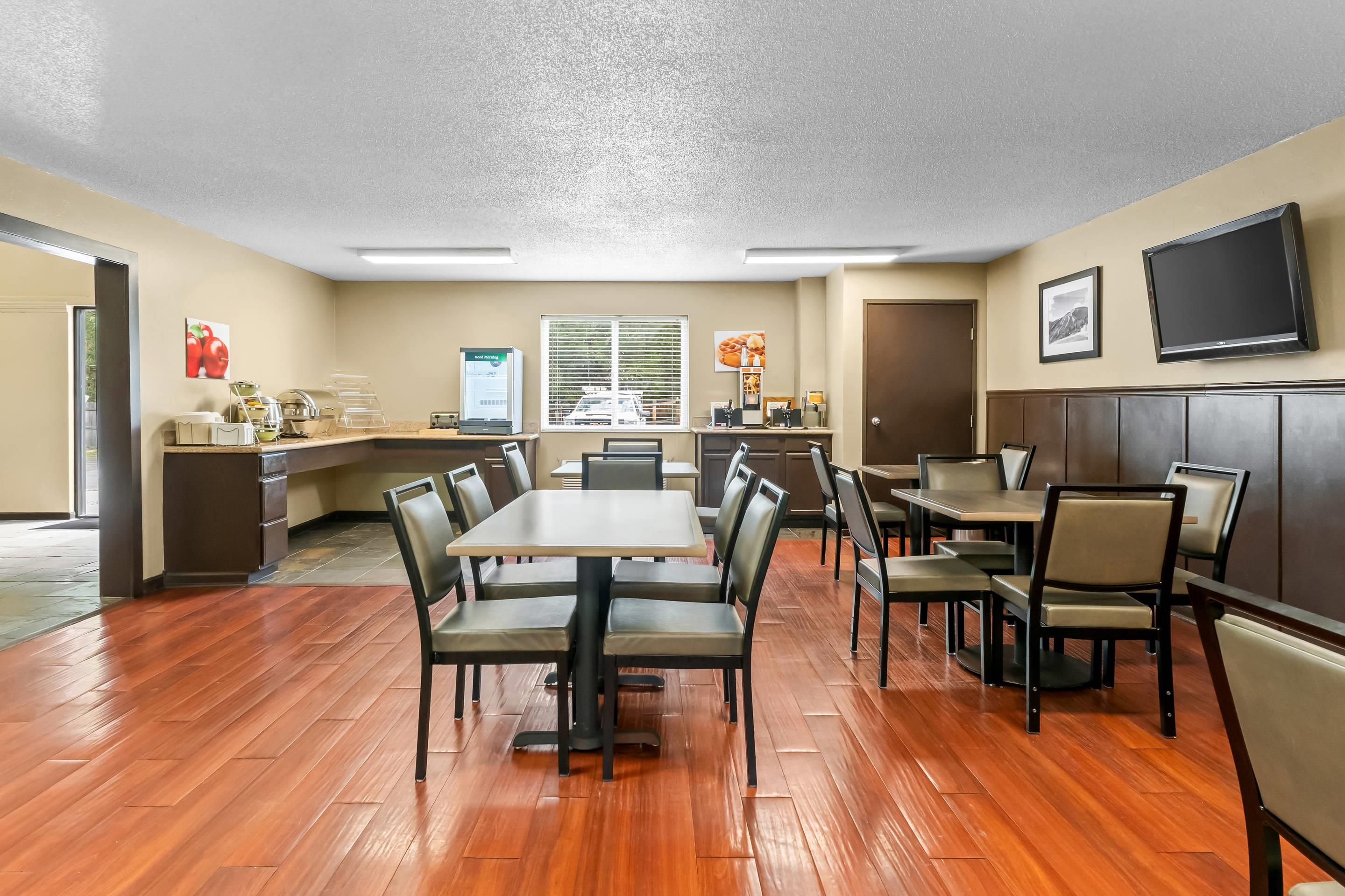 Une salle de conférence équipée d’une grande table et de chaises, d’un coin cuisine, d’une fenêtre et d’un téléviseur fixé au mur.