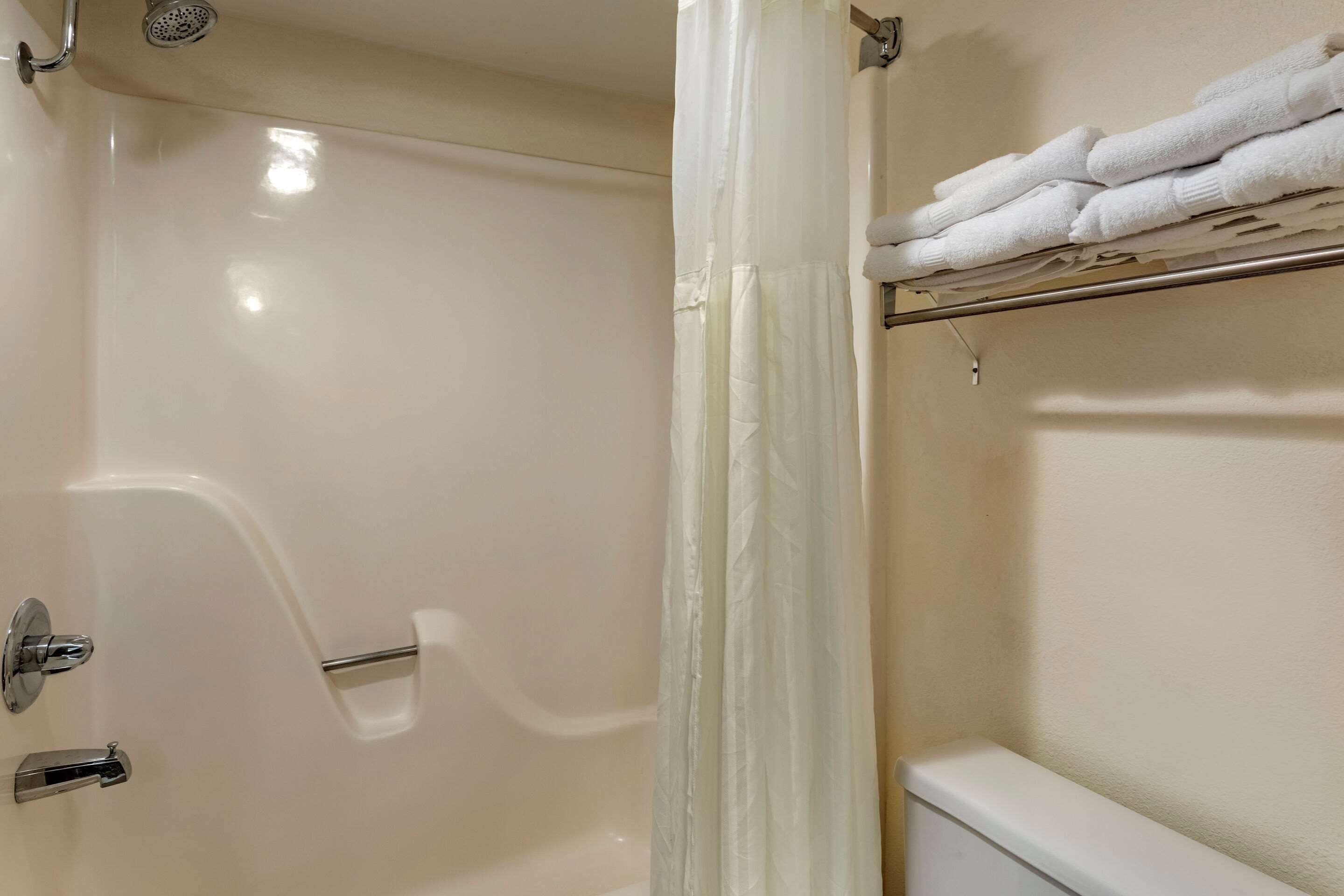 A bathroom with a bathtub, a shower, and a towel rack with folded towels.