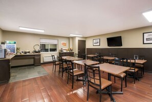 A hotel room with wooden flooring, a kitchenette, a flat-screen TV, and multiple tables and chairs. - Quality Inn & Suites Steamboat Springs (Steamboat Springs)