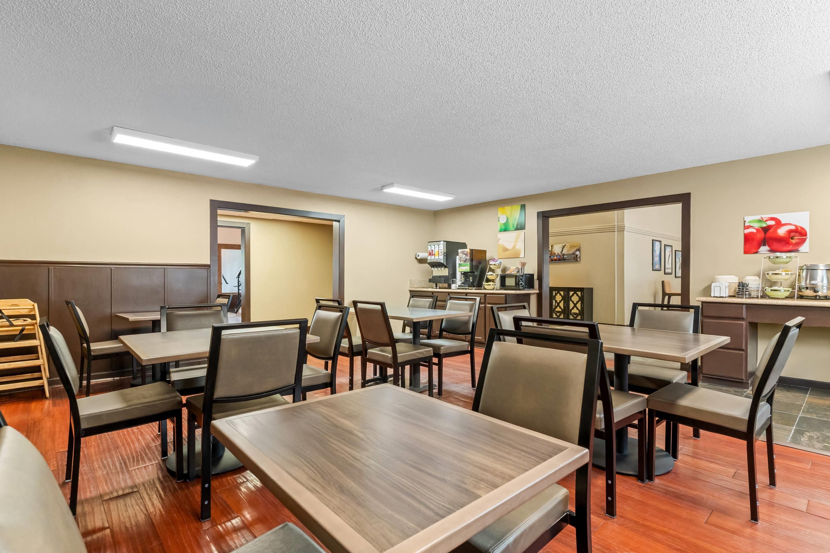 A hotel dining area with multiple tables and chairs, a coffee machine, and a counter with a microwave.