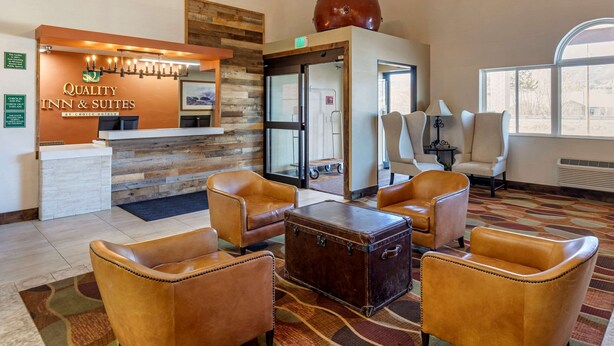A hotel reception area with leather chairs, a reception desk, and a large window. - Quality Inn & Suites Steamboat Springs (Steamboat Springs)