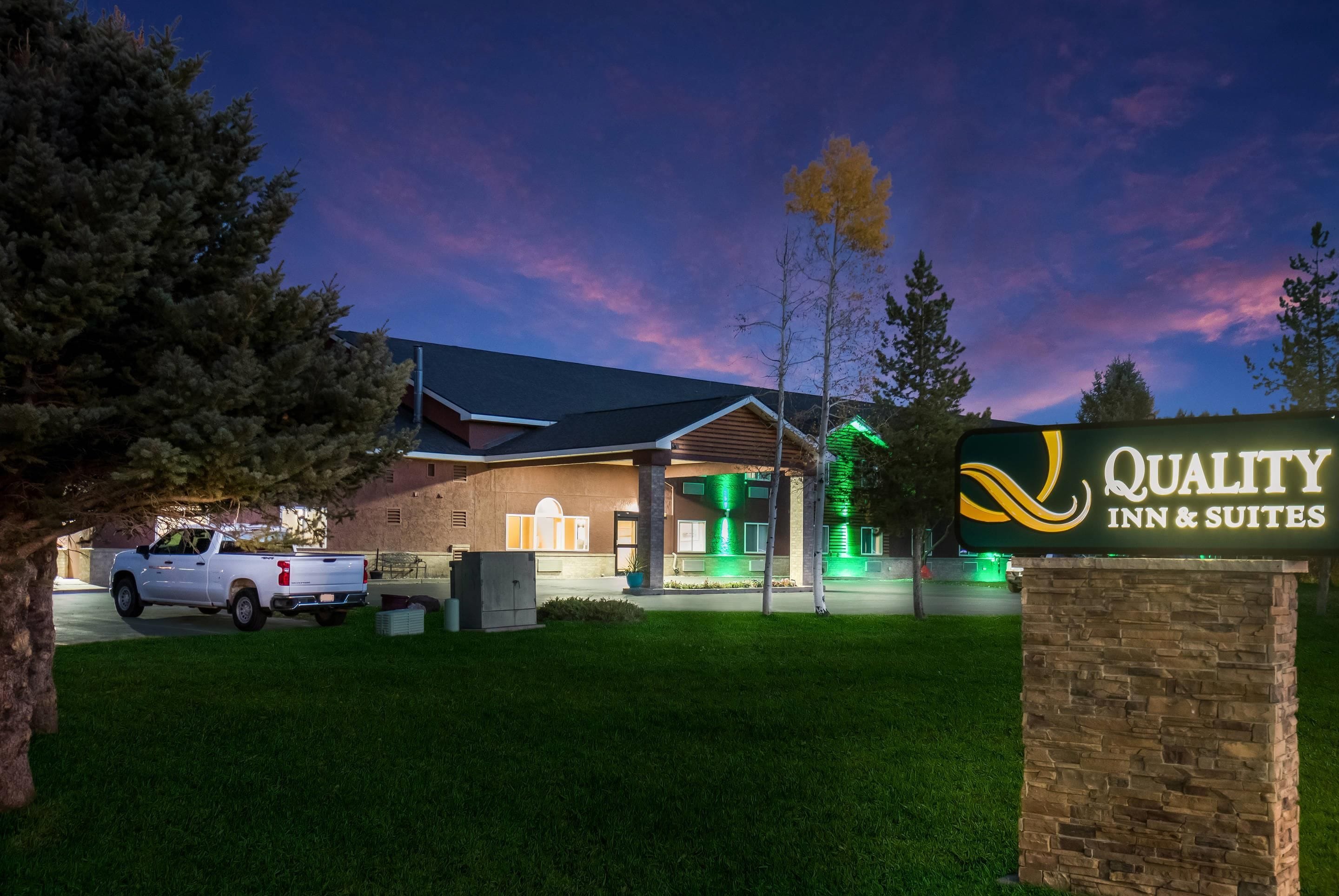 Een hotel met een bordje 'Quality Inn & Suites' en een witte pick-up truck ervoor geparkeerd.