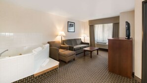 A hotel room with a large bathtub, a sofa, a small table, and a TV. - Quality Inn & Suites Steamboat Springs (Steamboat Springs)