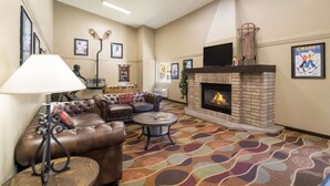A spacious living area with a fireplace, leather sofas, a coffee table, and a patterned carpet. - Quality Inn & Suites Steamboat Springs (Steamboat Springs)
