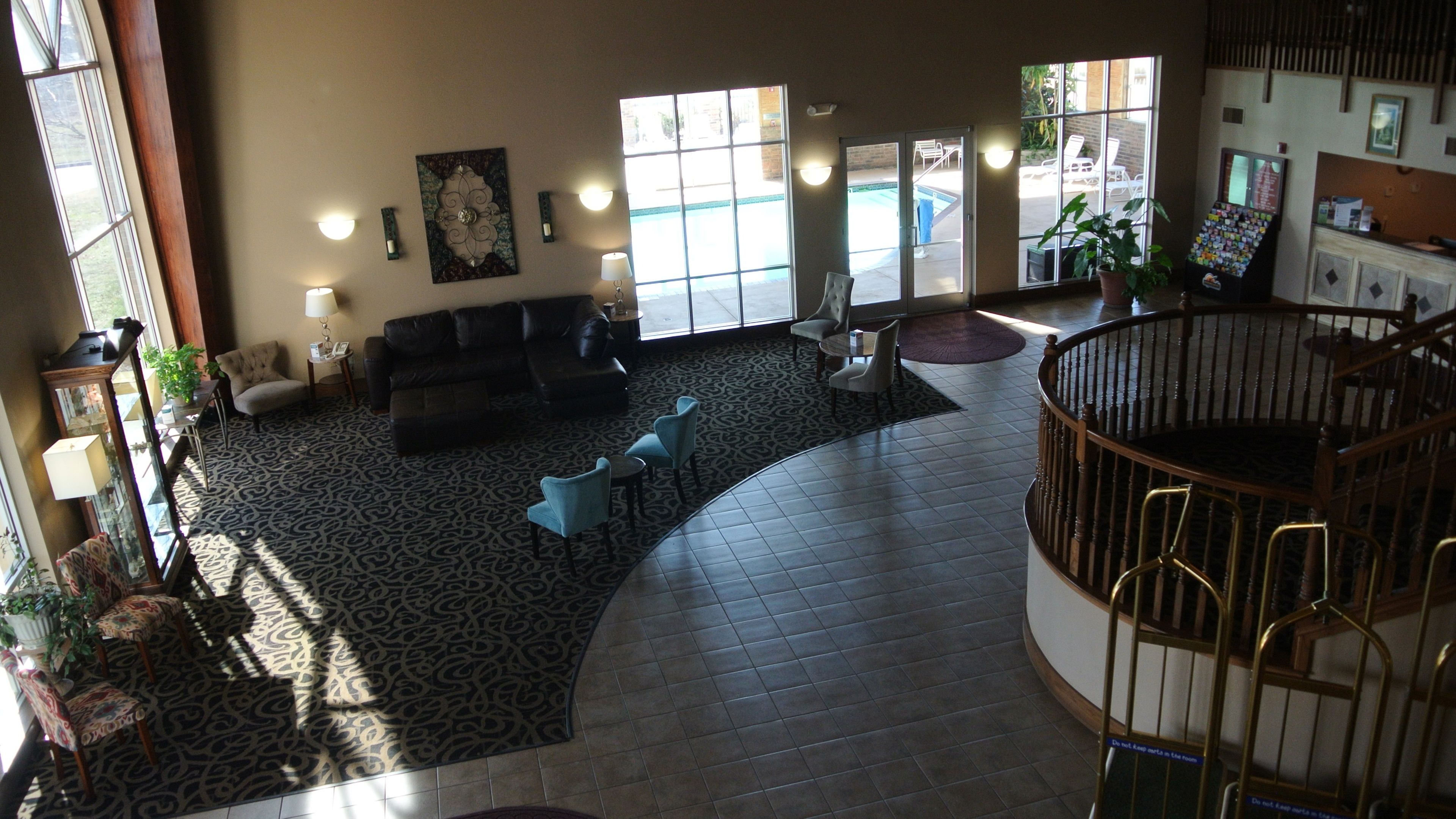 A spacious lobby with a black leather sofa, patterned carpet, and a staircase leading to an upper level.